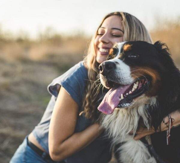 A girl smiling and hugging her dog.