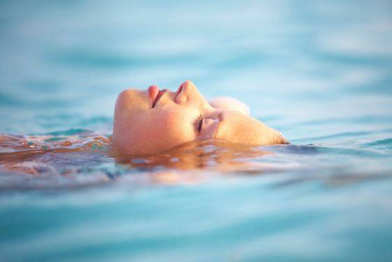 A woman peacefully floating face-up in a body of water.